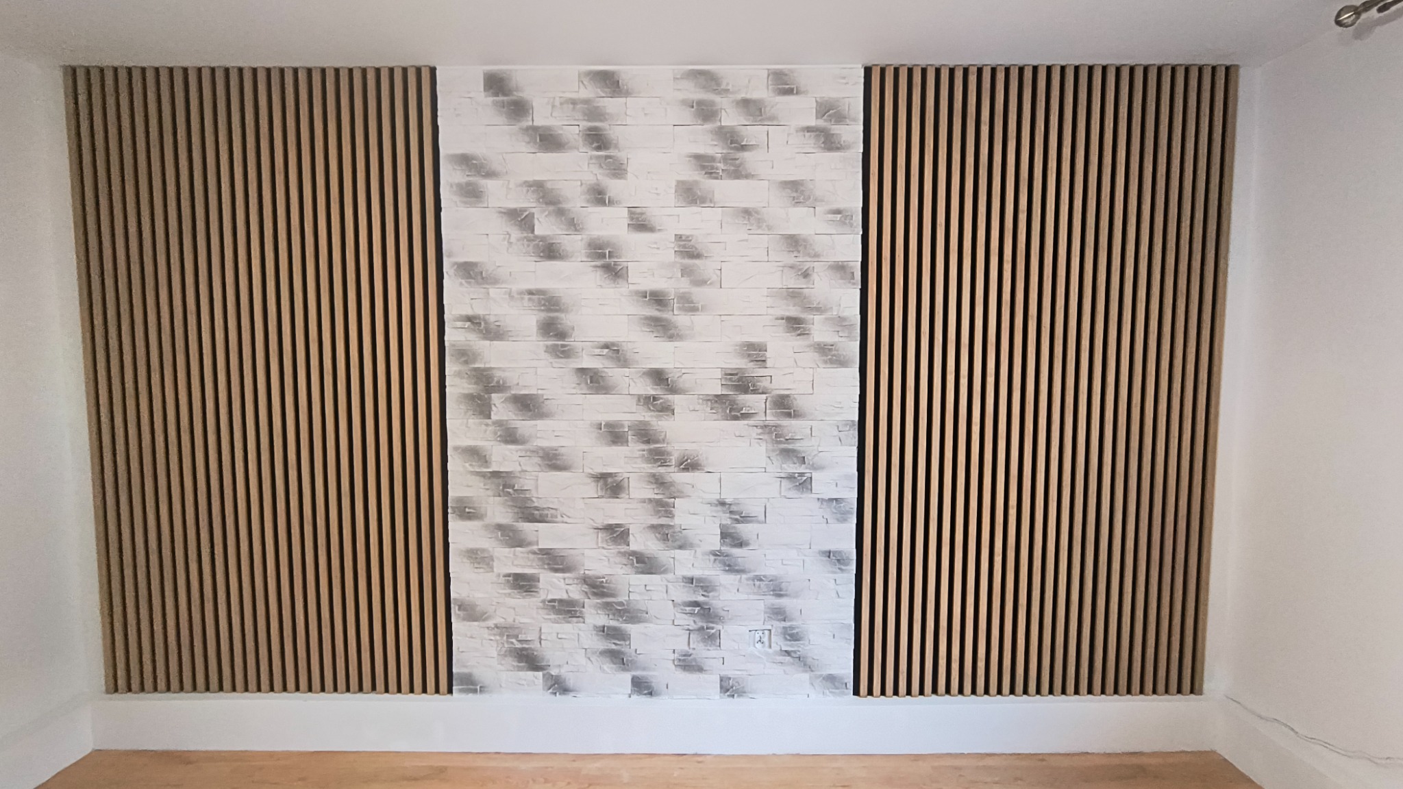 Ściana z dekoracyjnymi panelami lamelowymi po bokach i tapetą imitującą cegłę na środku. Nowoczesne wykończenie wnętrza, widok na całą ścianę.