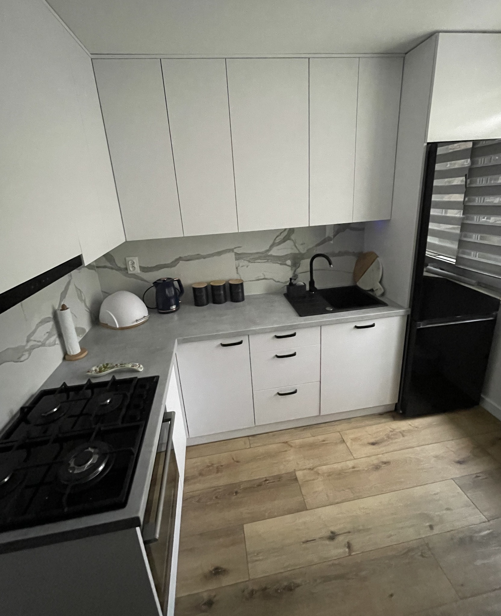 Kuchnia wykonana z płyty Biała Alaska o strukturze matowej z czarnymi dodatkami