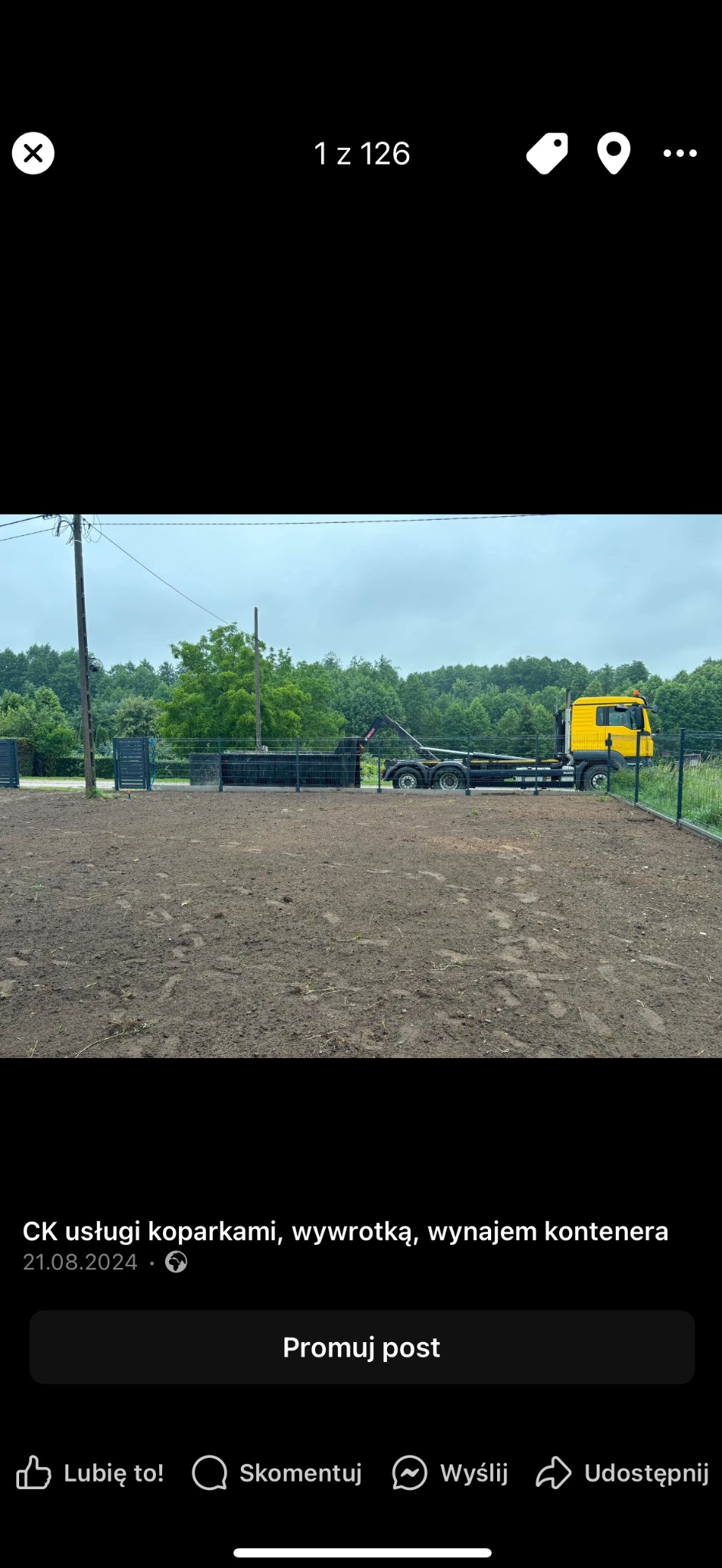 Przygotowany teren z wywiezioną ziemią, widoczny kontener i żółta ciężarówka z hakiem, ogrodzenie z siatki.