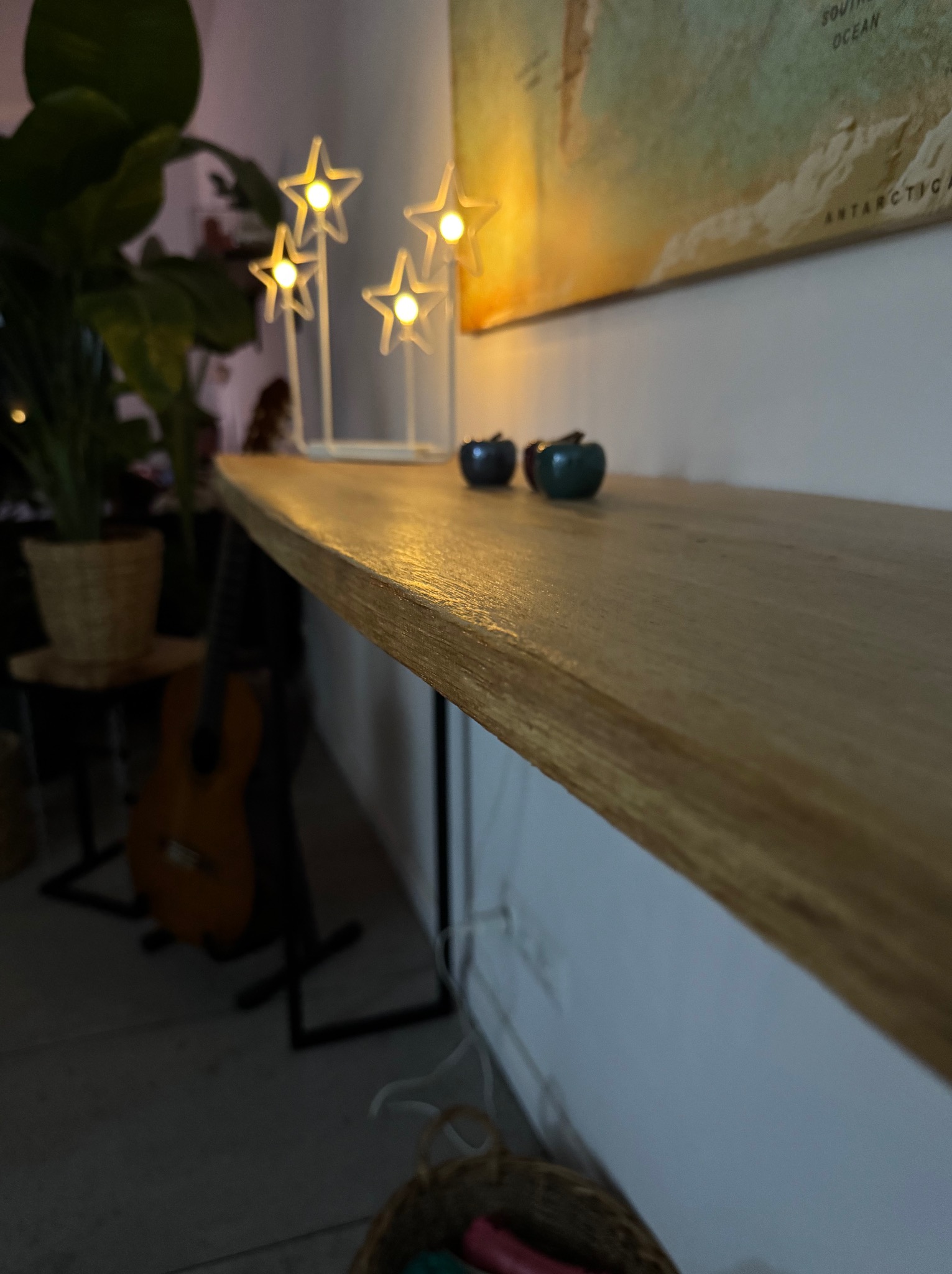 Dębowa półka ścienna z widocznym usłojeniem drewna, oświetlona przez lampki w kształcie gwiazd, z dekoracyjnymi jabłkami i rośliną doniczkową w tle.