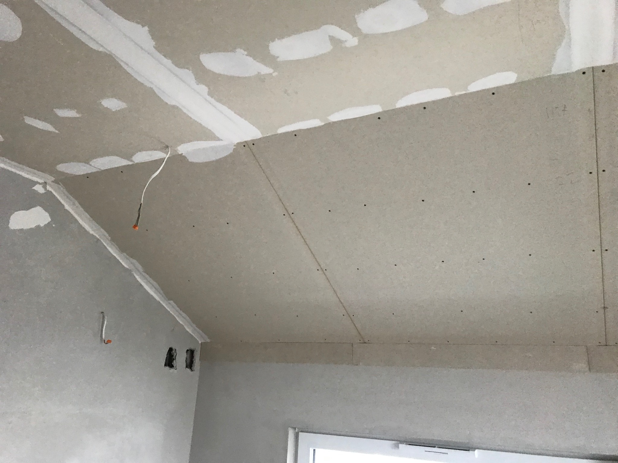 Montaż płyty karton gips na suficie poddasza w Ostrołęce, widoczne łączenia płyt zaszpachlowane i wystający przewód elektryczny.