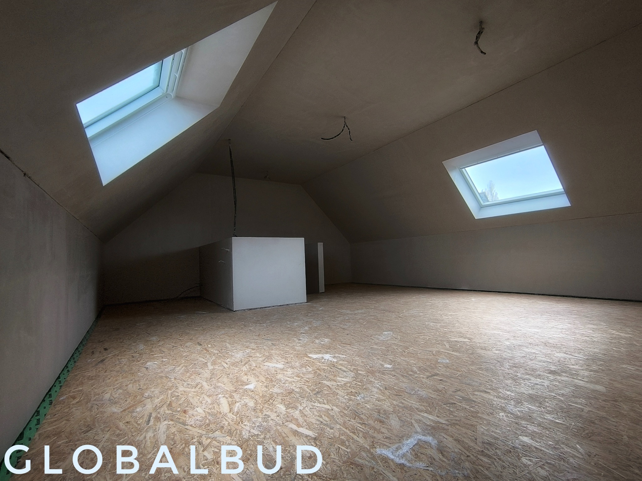 Poddasze z oknami dachowymi po nałożeniu tynku, widoczne kable wystające ze ściany, podłoga z płyt OSB.