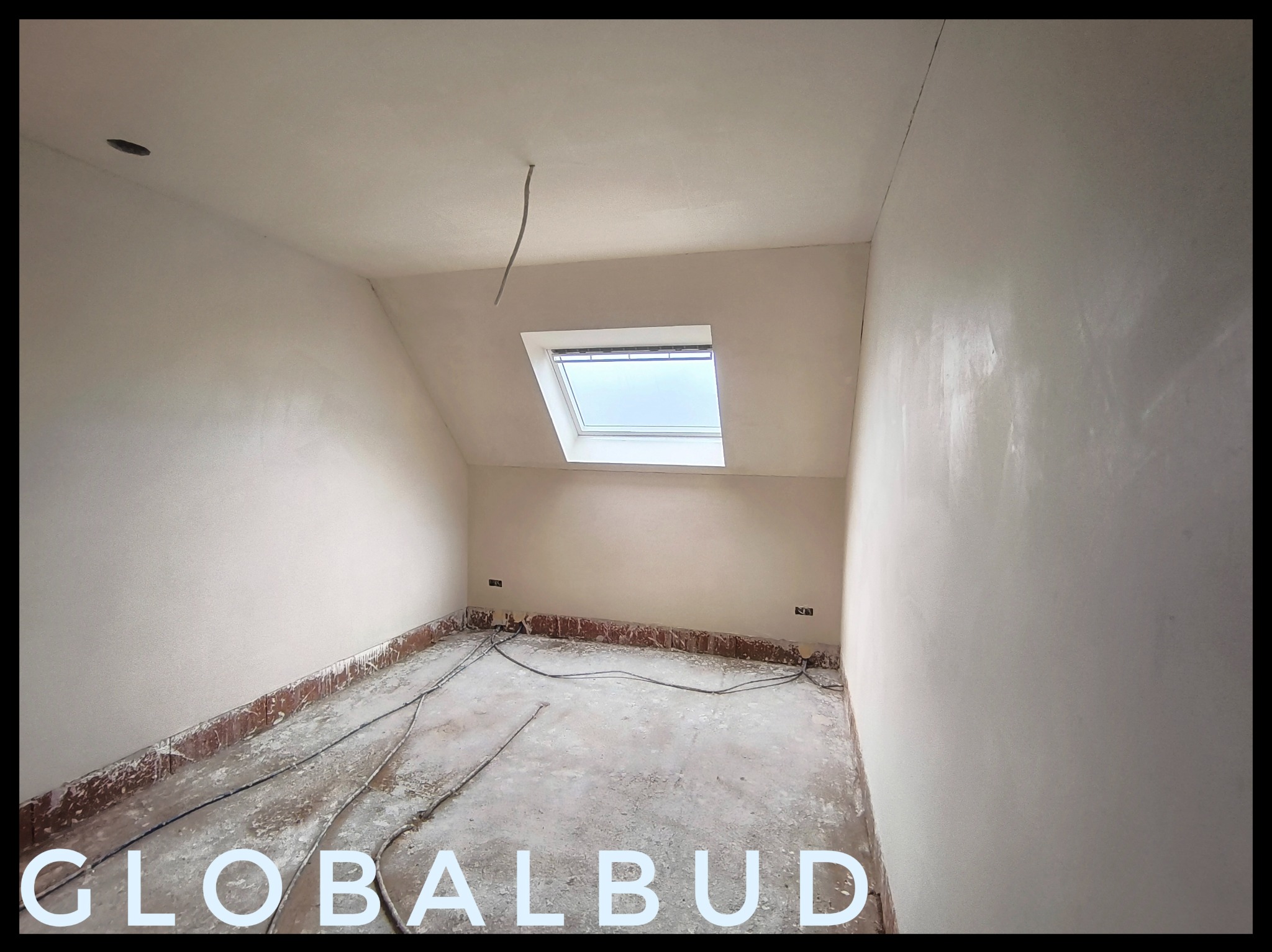 Pokój na poddaszu po tynkowaniu maszynowym, widoczne gładkie ściany, okno dachowe i wystające kable z sufitu, przygotowany do dalszych prac wykończeniowych.