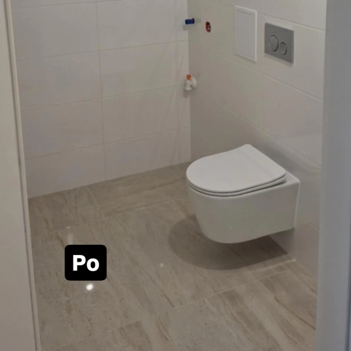 Wykończona łazienka z podwieszaną toaletą i beżowymi płytkami podłogowymi. Widoczny fragment napisu 'Po' sugeruje zdjęcie typu 'przed i po'.