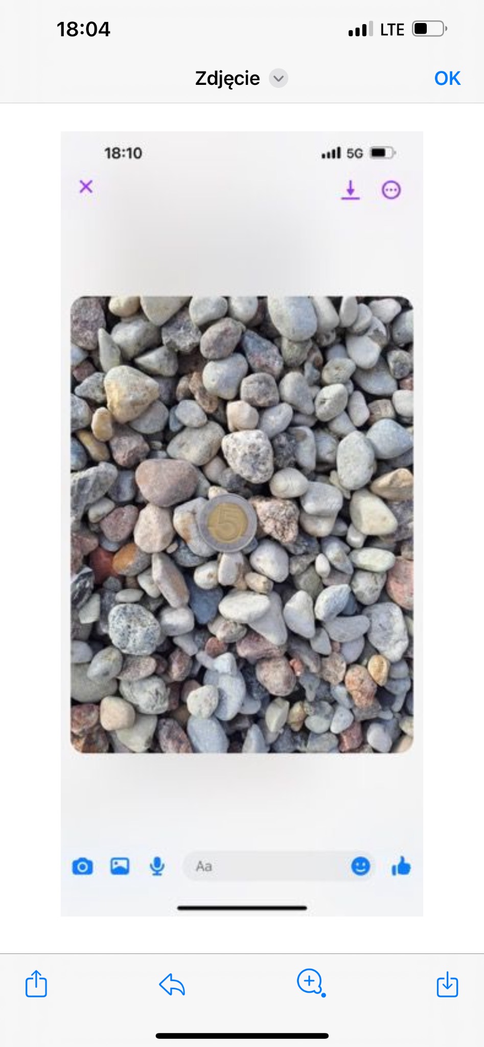 Żwir o różnych odcieniach szarości i brązu z monetą 5 zł dla porównania rozmiaru, sfotografowany w naturalnym świetle.