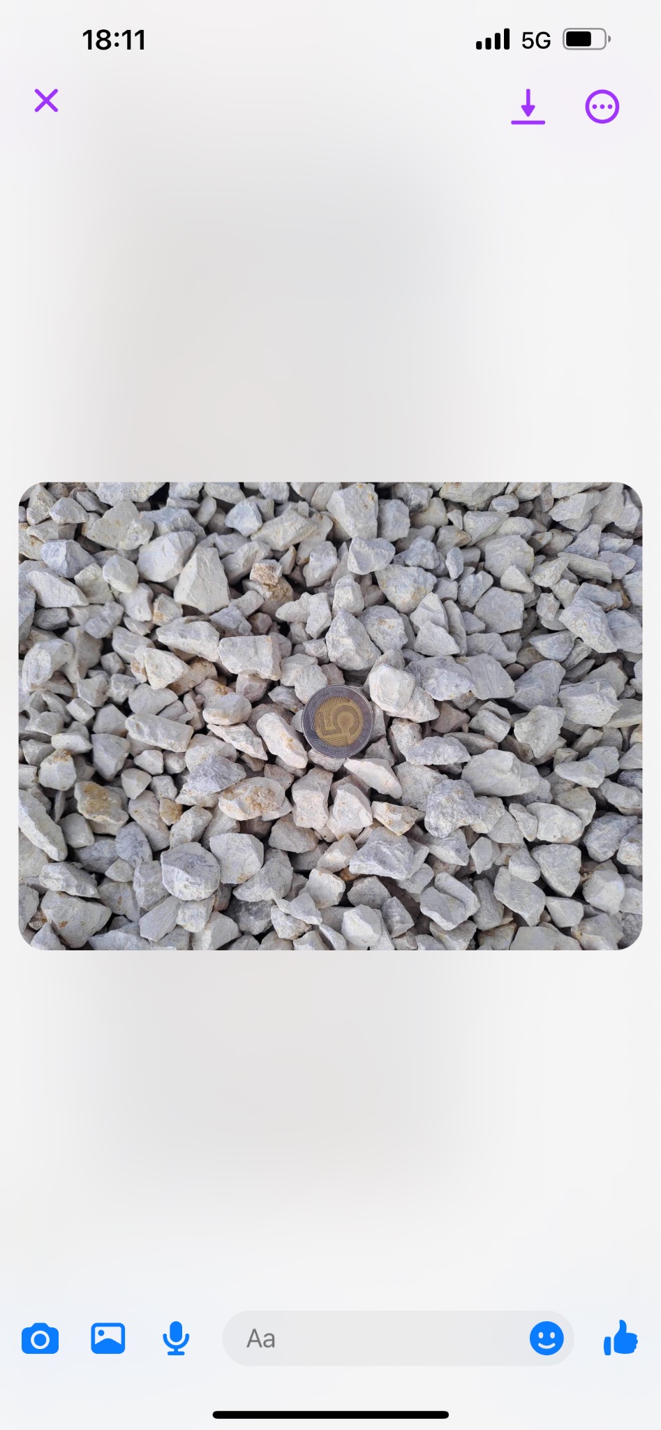 Drobne, białe kruszywo kamienne z monetą 5 zł dla porównania skali, ułożone na płaskiej powierzchni.