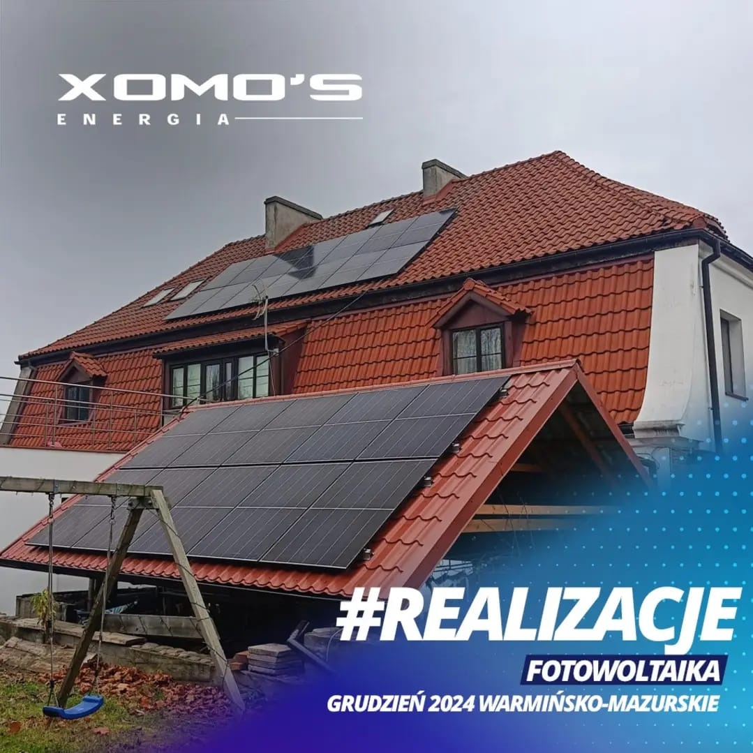 Instalacja fotowoltaiczna na dachu domu z czerwoną dachówką, widoczny huśtawka, logo firmy XOMO'S Energia i oznaczenie #REALIZACJE Grudzień 2024 Warmińsko-Mazurskie.