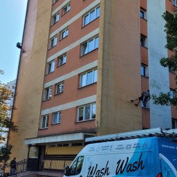 WASH WASH PIOTR REPLIN - Pracownik na linach myje elewację wysokiego budynku, widoczny firmowy samochód z napisem 'Wash Wash' oraz numerem telefonu.