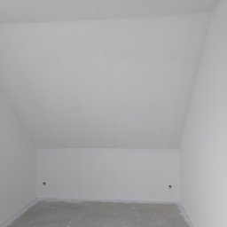 Grzegorz Bitner - Poddasze po szpachlowaniu i gruntowaniu ścian, widoczne gniazdka elektryczne, surowy beton na podłodze, przygotowane do dalszych prac wykończeniowych.