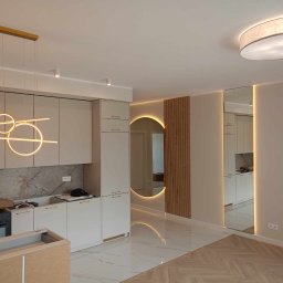 VIK-BUD VIKTOR SYDORCHUK - Wnętrze mieszkania w trakcie remontu: widoczna zabudowa kuchenna z marmurowym backsplashiem, nowoczesne oświetlenie wiszące, lustro z podświetleniem LED oraz fragment podłogi z białego marmuru...