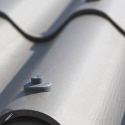 M.A.M. DREWNO MARCIN STACHOWIAK - Szczegółowy widok na szare dachówki ceramiczne z widocznymi elementami mocującymi, ułożone w falisty wzór. Ujęcie z bliska, z ostrością na fakturę i detale.