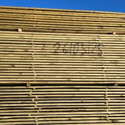 M.A.M. DREWNO MARCIN STACHOWIAK - Stos tarcicy budowlanej, spięty zielonymi taśmami, z napisem '241012' na środkowych deskach, na tle błękitnego nieba.