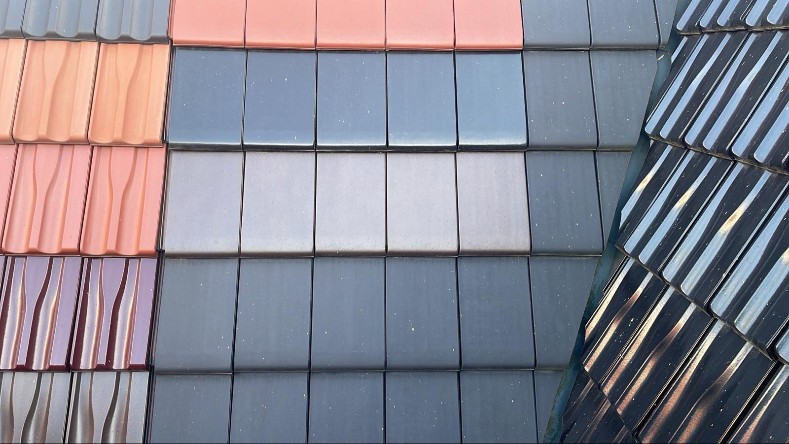 Ekspozycja różnokolorowych dachówek ceramicznych o różnych kształtach. Prezentacja różnych wariantów pokrycia dachowego, w tym błyszcząca czerń.