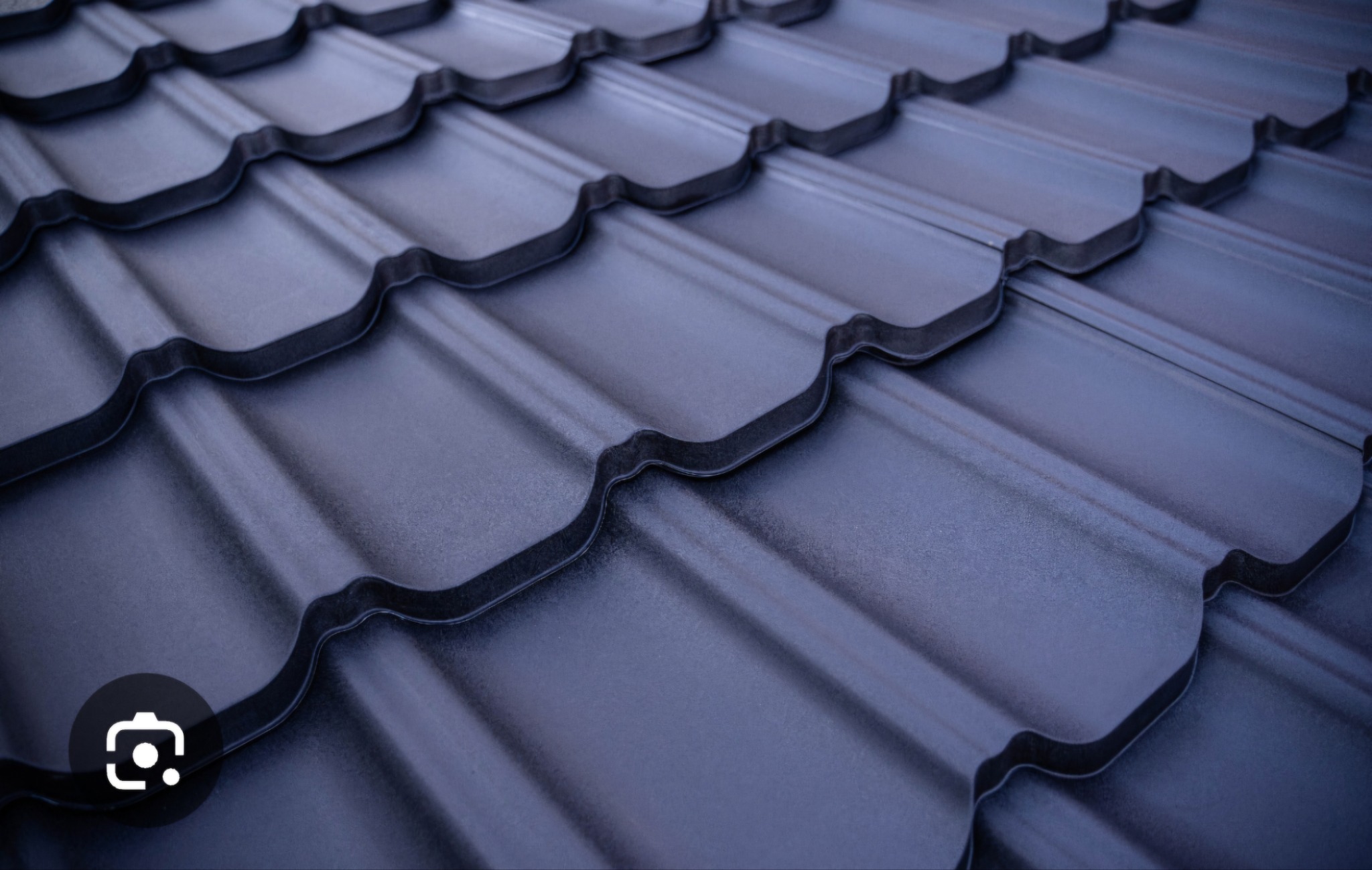 Ciemnoszare dachówki metalowe, ułożone pod kątem, z widoczną fakturą i detalami łączeń.