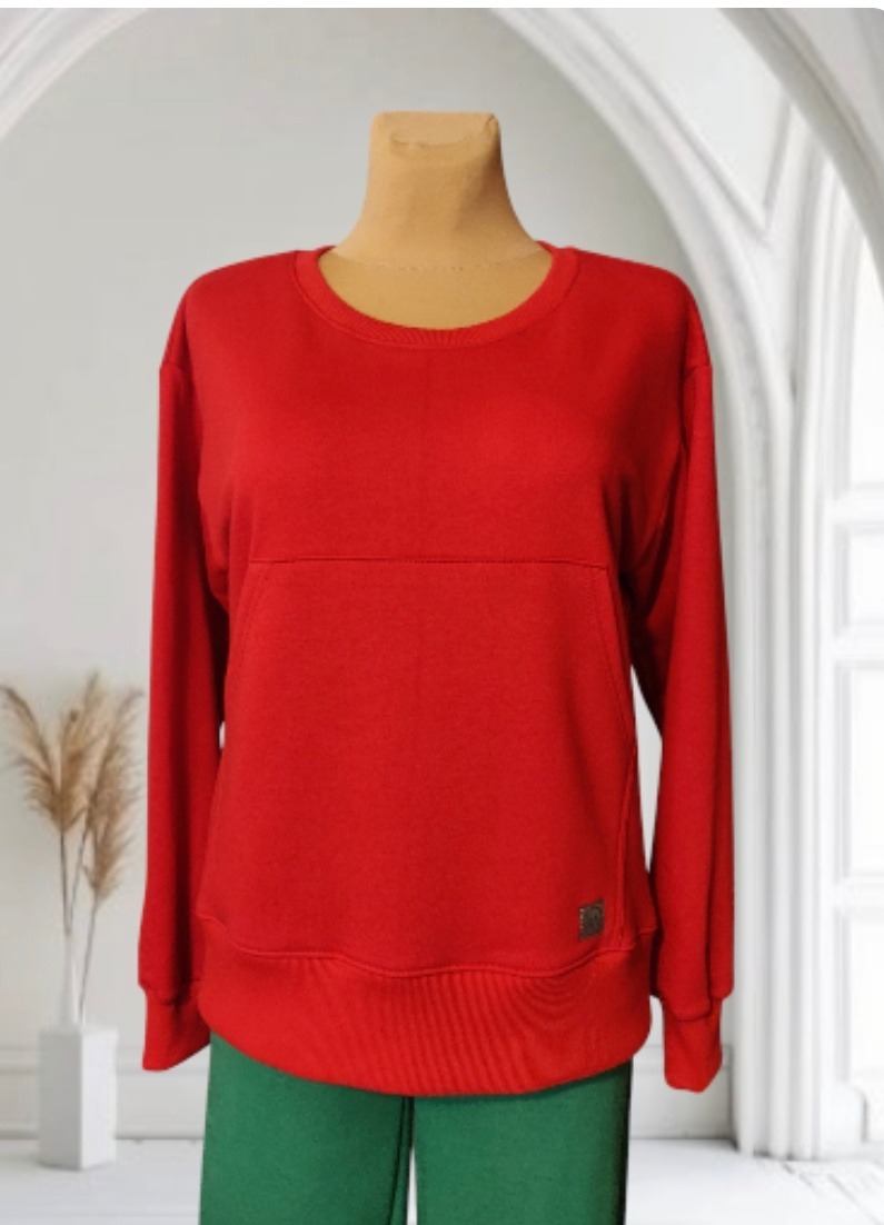 Czerwona bluza dresowa z długim rękawem, prezentowana na manekinie w Gdańsku, z widocznym detalem w postaci małej, metalowej plakietki z logo na dole.