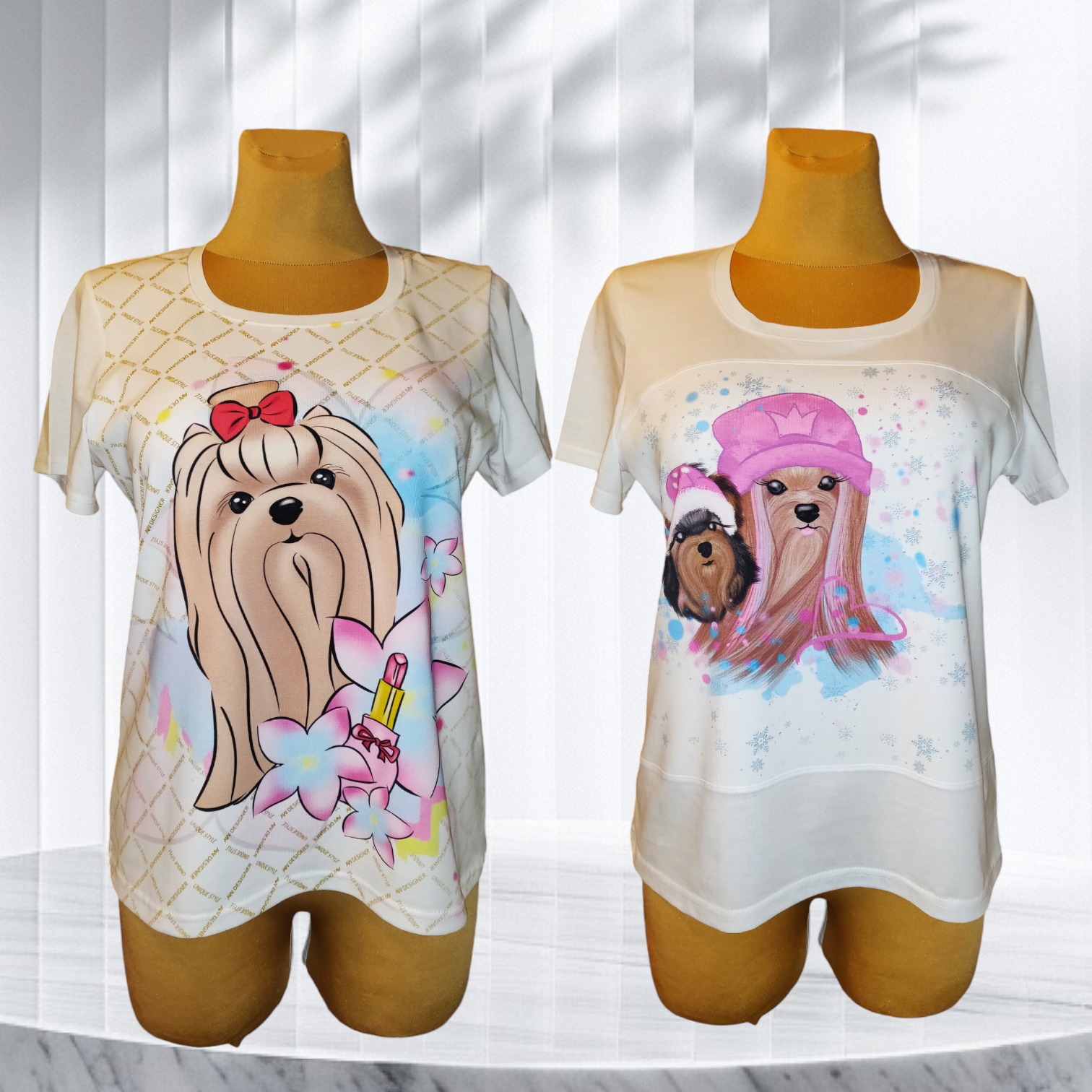 Dwa białe T-shirty damskie z krótkim rękawem, każdy z innym, kolorowym nadrukiem piesków w stylu kreskówkowym na manekinie, na tle białych, pionowych żaluzji.