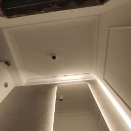 Andrzej Jeleń - Fragment sufitu z dekoracyjną sztukaterią i przygotowanym otworem na oświetlenie, widoczne niedokończone prace wykończeniowe w górnej części kadru.