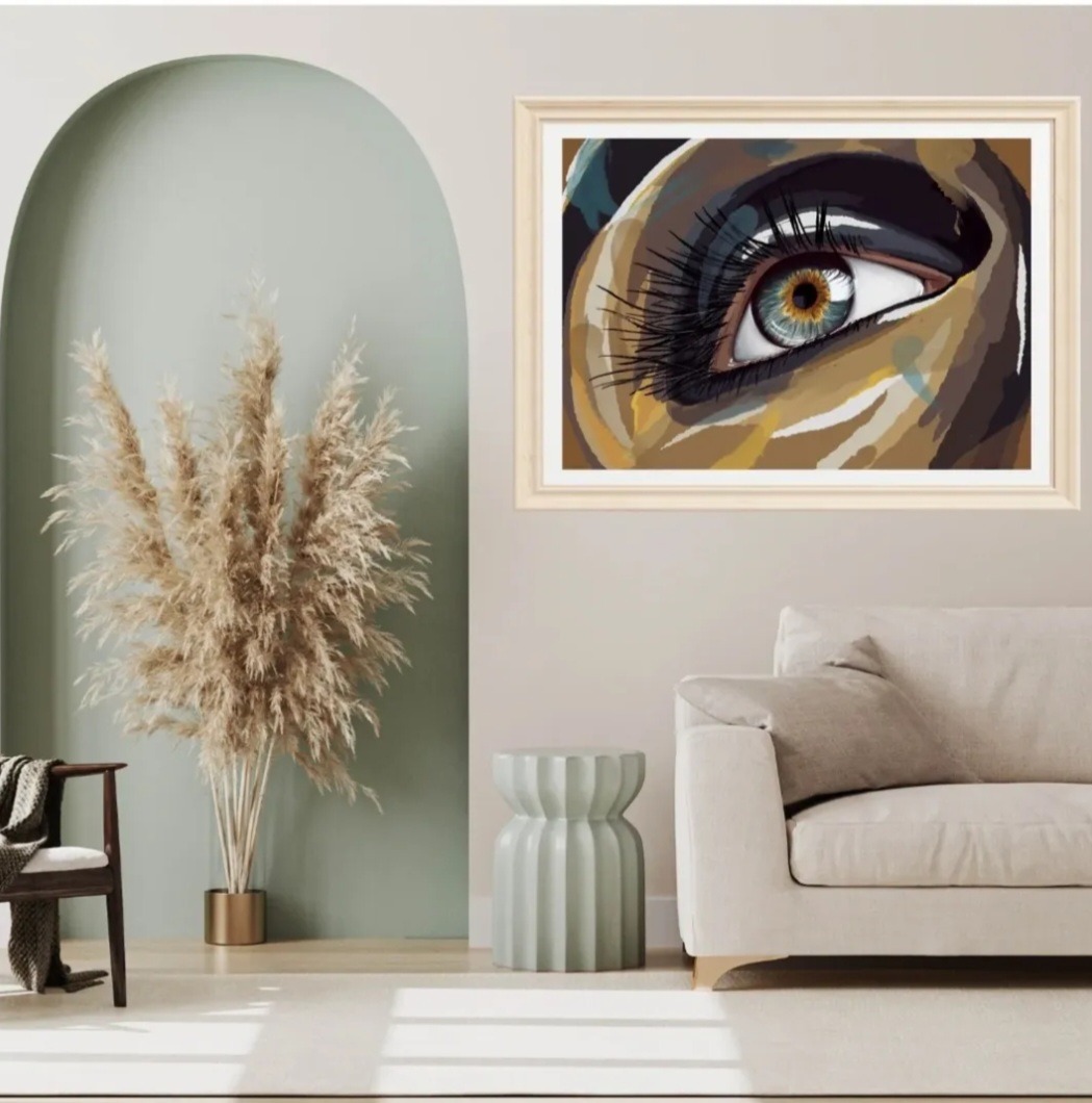 Wnętrze z obrazem oka w ramie, w stylu abstrakcyjnym. Obraz wisi nad kanapą, obok dekoracyjna trawa w złotym wazonie i krzesło z pledem.