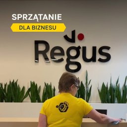 Simplebee Khrystyna Kuzmenko - Pracownica w żółtej koszulce z logo firmy sprzątającej przeciera blat recepcji w biurze Regus, widoczne rośliny doniczkowe i napis Sprzątanie dla biznesu.