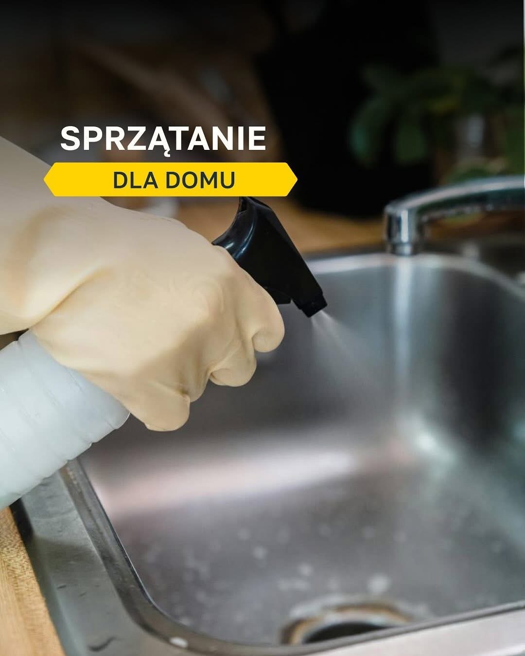 Osoba w lateksowej rękawicy spryskuje stalowy zlew środkiem czyszczącym z czarnego rozpylacza.