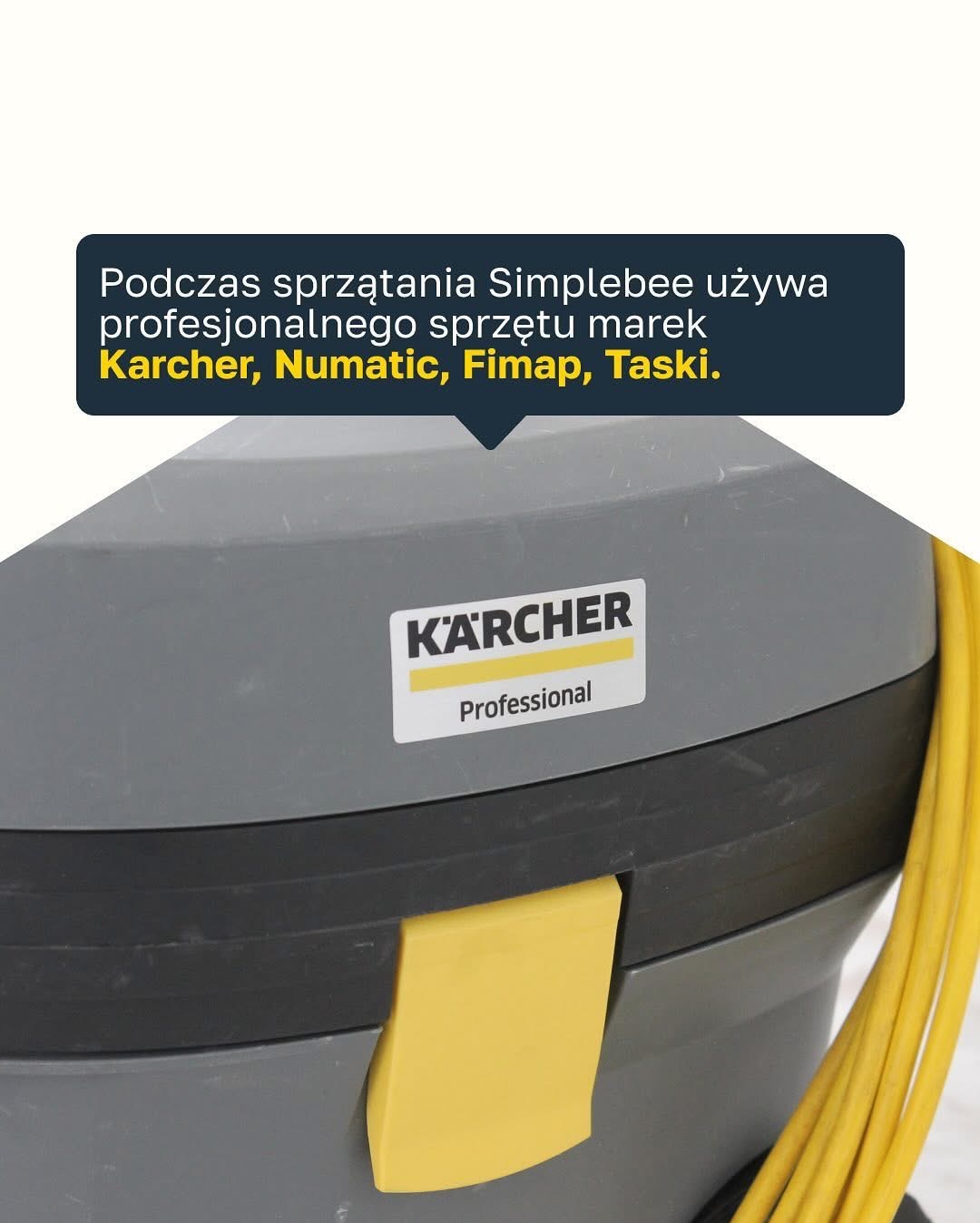 Szary odkurzacz przemysłowy marki Kärcher Professional z żółtym kablem, widok z bliska na etykietę producenta i zatrzask. Odkurzacz sugeruje profesjonalne usługi porządkowe.