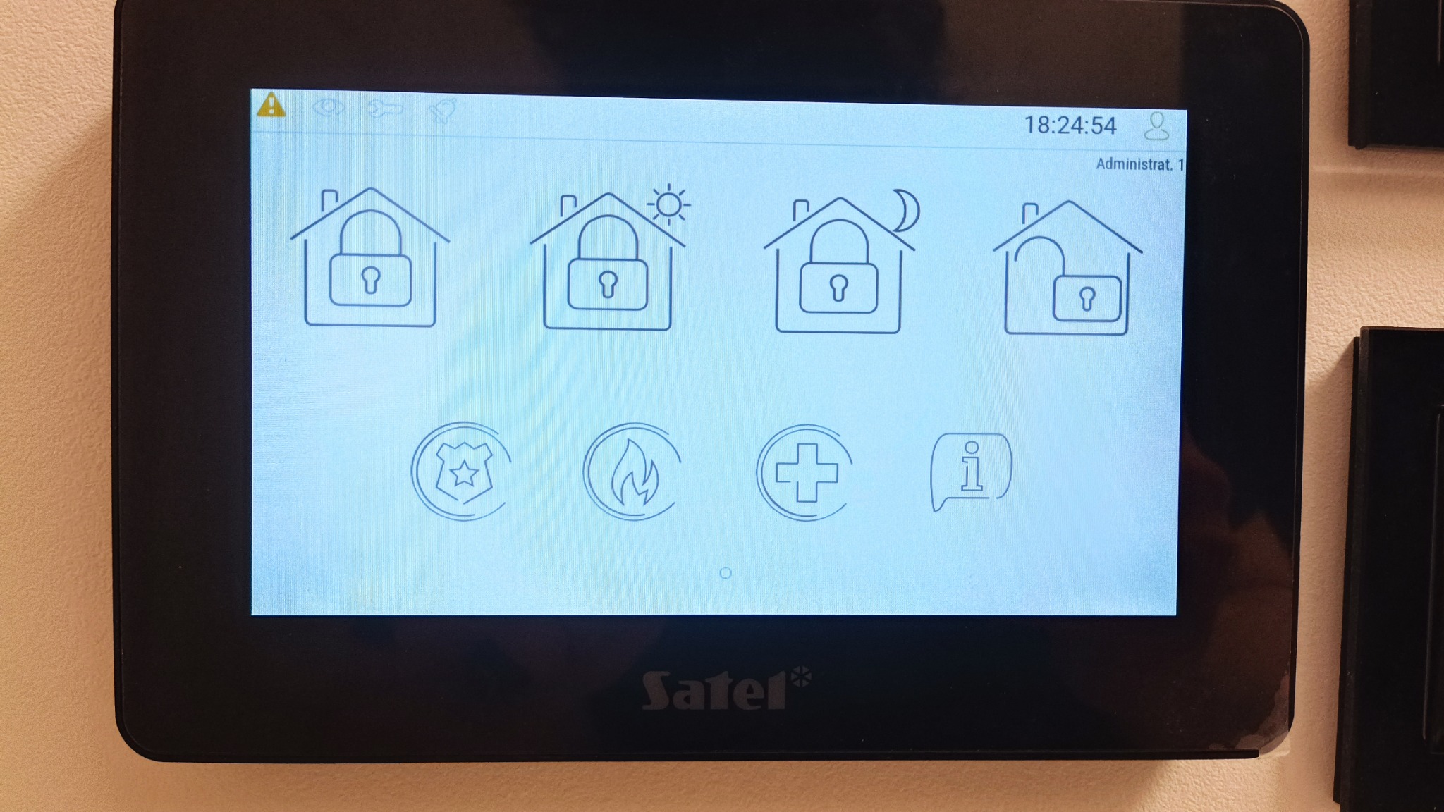 Ekran dotykowy centrali alarmowej Satel, wyświetlający graficzne ikony stanu zabezpieczeń domu w różnych porach dnia, z widocznym panelem administracyjnym.