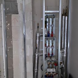 ,,BRODA-BUD” PRZEMYSŁAW MASTERNAK - Konstrukcja metalowa pod zabudowę z instalacją grzewczą i wodną wewnątrz, widoczne rury w izolacji, manometry i liczniki, surowy stan wykończenia, ściany z bloczków.