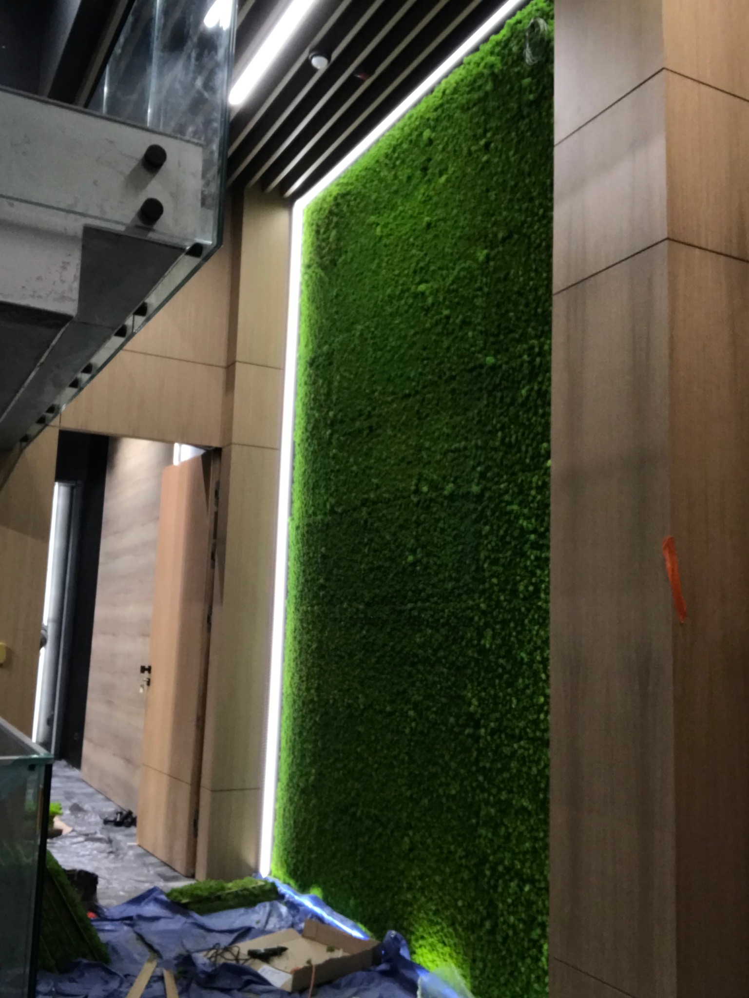 Montaż ściany z mchu w biurze w Piekarach Śląskich, widoczne przygotowania i narzędzia na podłodze.