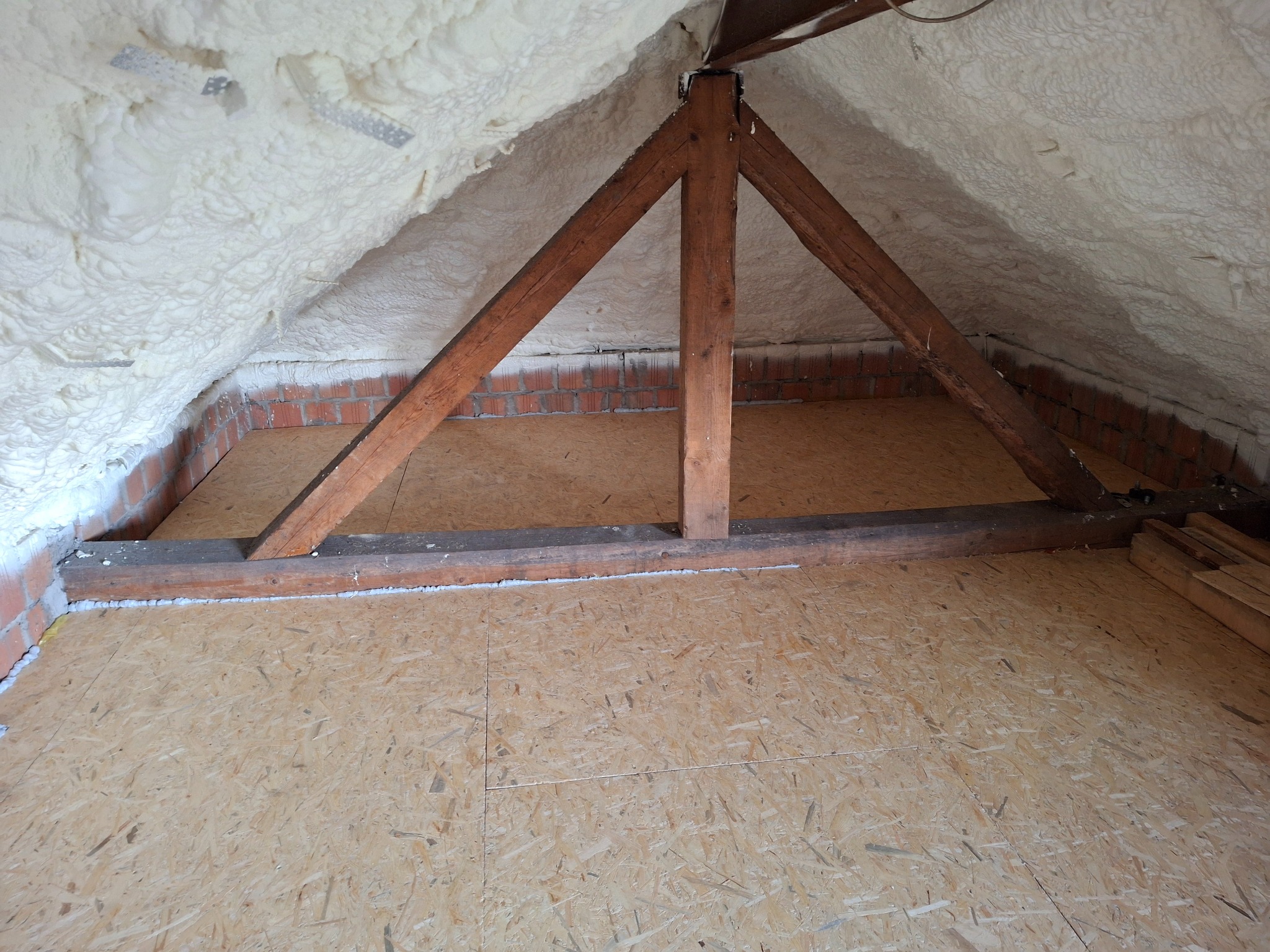 Poddasze w Jastrzębiu-Zdroju po ociepleniu pianą PUR, widoczne drewniane elementy konstrukcyjne i płyty OSB na podłodze.