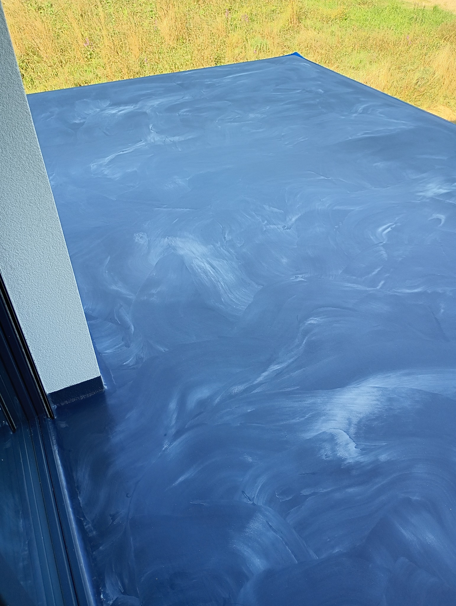 Niebieska posadzka z efektem marmuru w jasnym pomieszczeniu, widok z góry na gładką, błyszczącą powierzchnię z delikatnymi, białymi smugami.