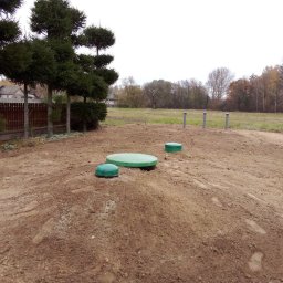Hydrotech Tomasz Zglinicki - Instalacja ekologicznej oczyszczalni: widoczne trzy zielone pokrywy zbiorników oraz cztery pionowe rury odpowietrzające na wykopanym terenie.