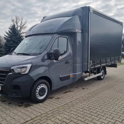 ANATOLII KUCHEREVSKYI - Szary samochód dostawczy Renault Master Twin Cab z plandeką na parkingu z kostki brukowej, widok z przodu i boku.