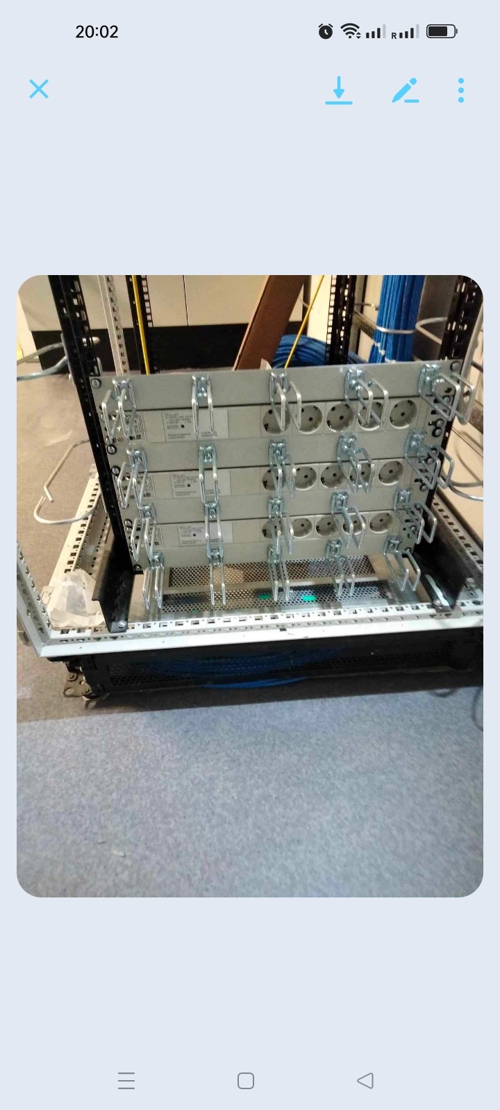 Cztery listwy z gniazdami elektrycznymi zamontowane w metalowej szafie rack, widoczne metalowe uchwyty montażowe i otwory gniazd, w tle kable i elementy instalacji.