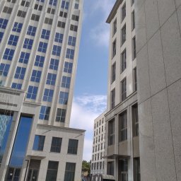 PPUH Pierlak szymon - Dwa budynki biurowe o nowoczesnej architekturze, z widocznym fragmentem nieba, oraz przenośne toalety na chodniku.