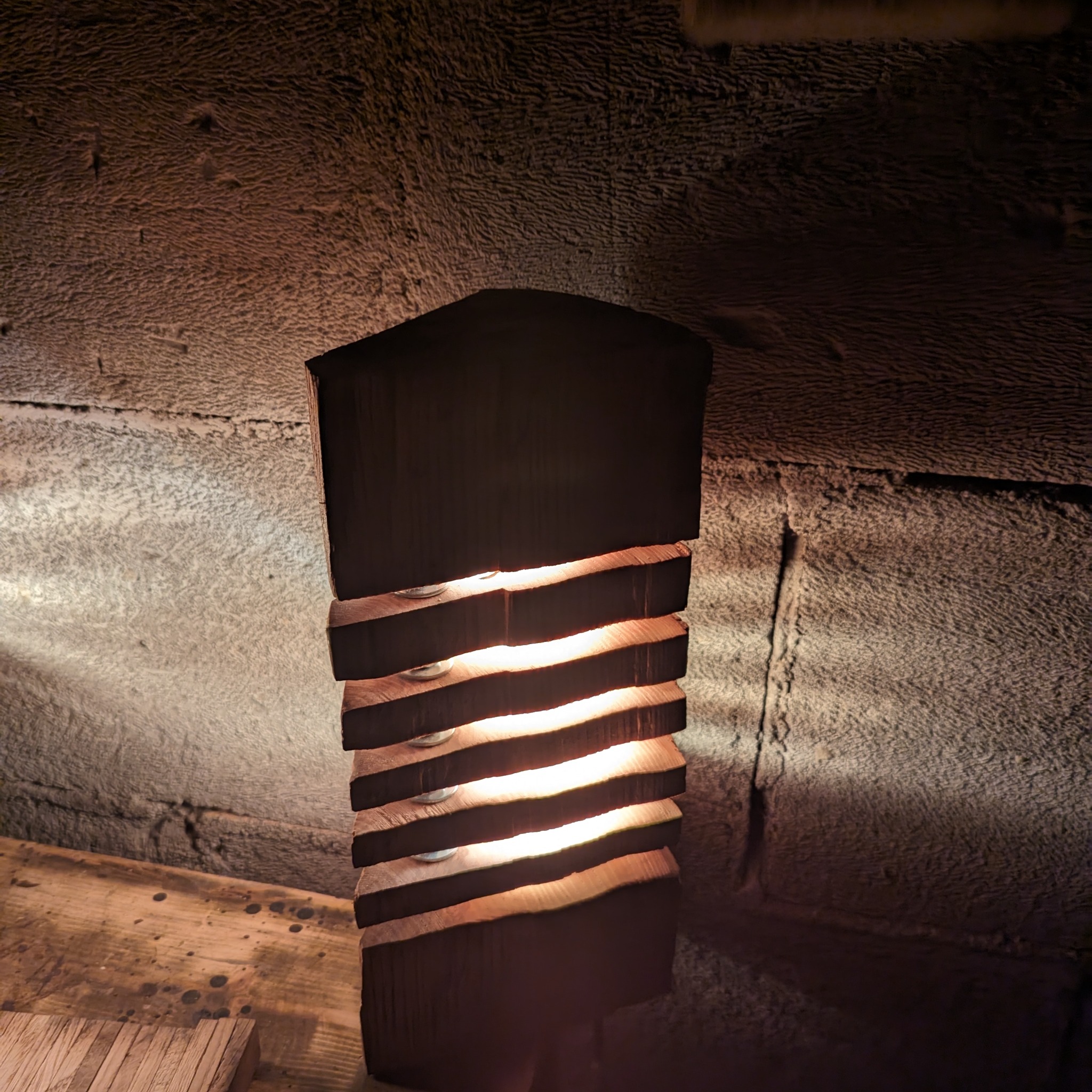 Ocieplone poddasze z widoczną drewnianą konstrukcją lampy z żarówkami, ciepłe oświetlenie tworzy przytulną atmosferę.