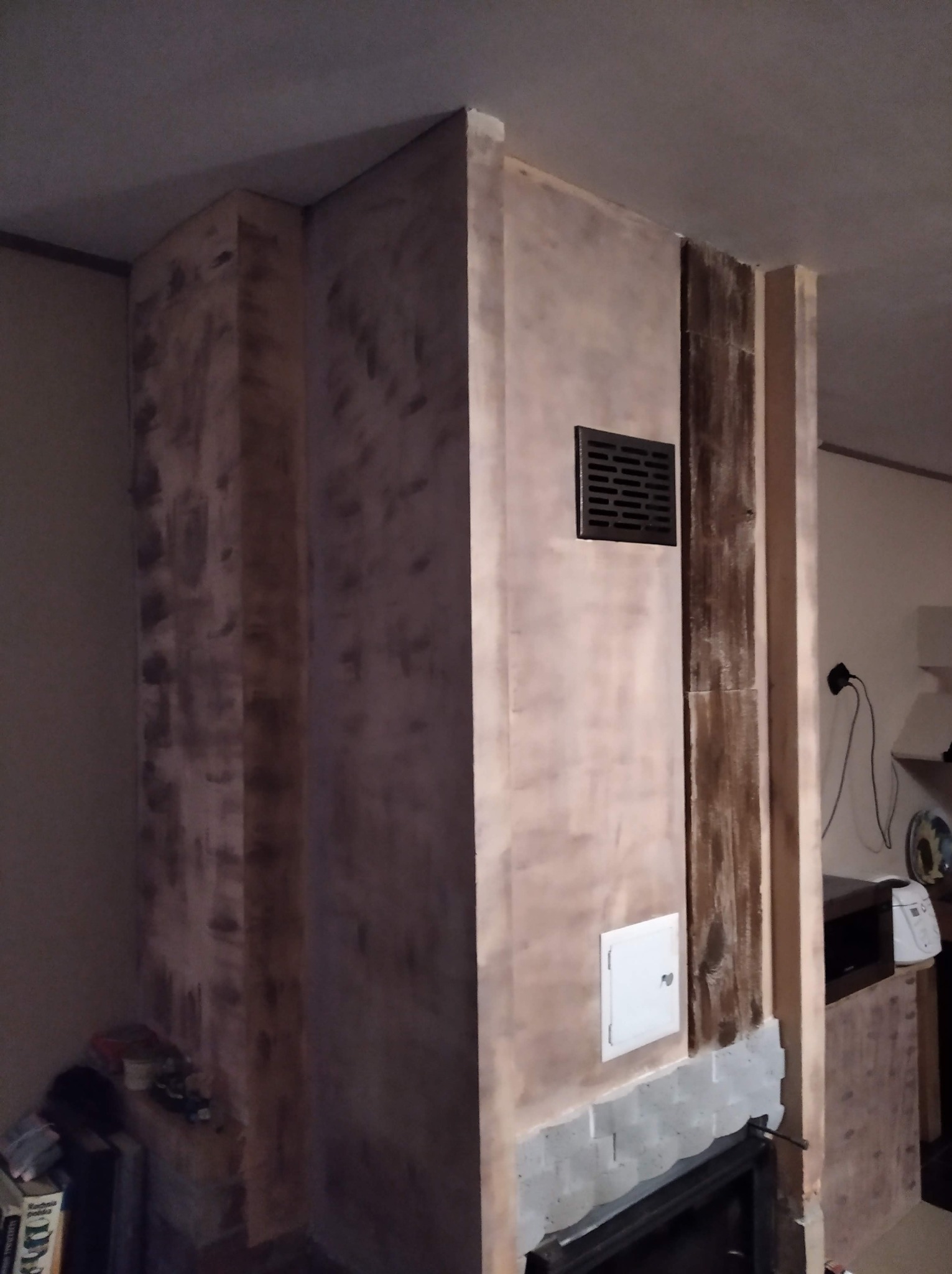 Ściana kominkowa w trakcie szpachlowania w Sopotni Wielkiej, widoczne ślady po szpachli i kratka wentylacyjna.