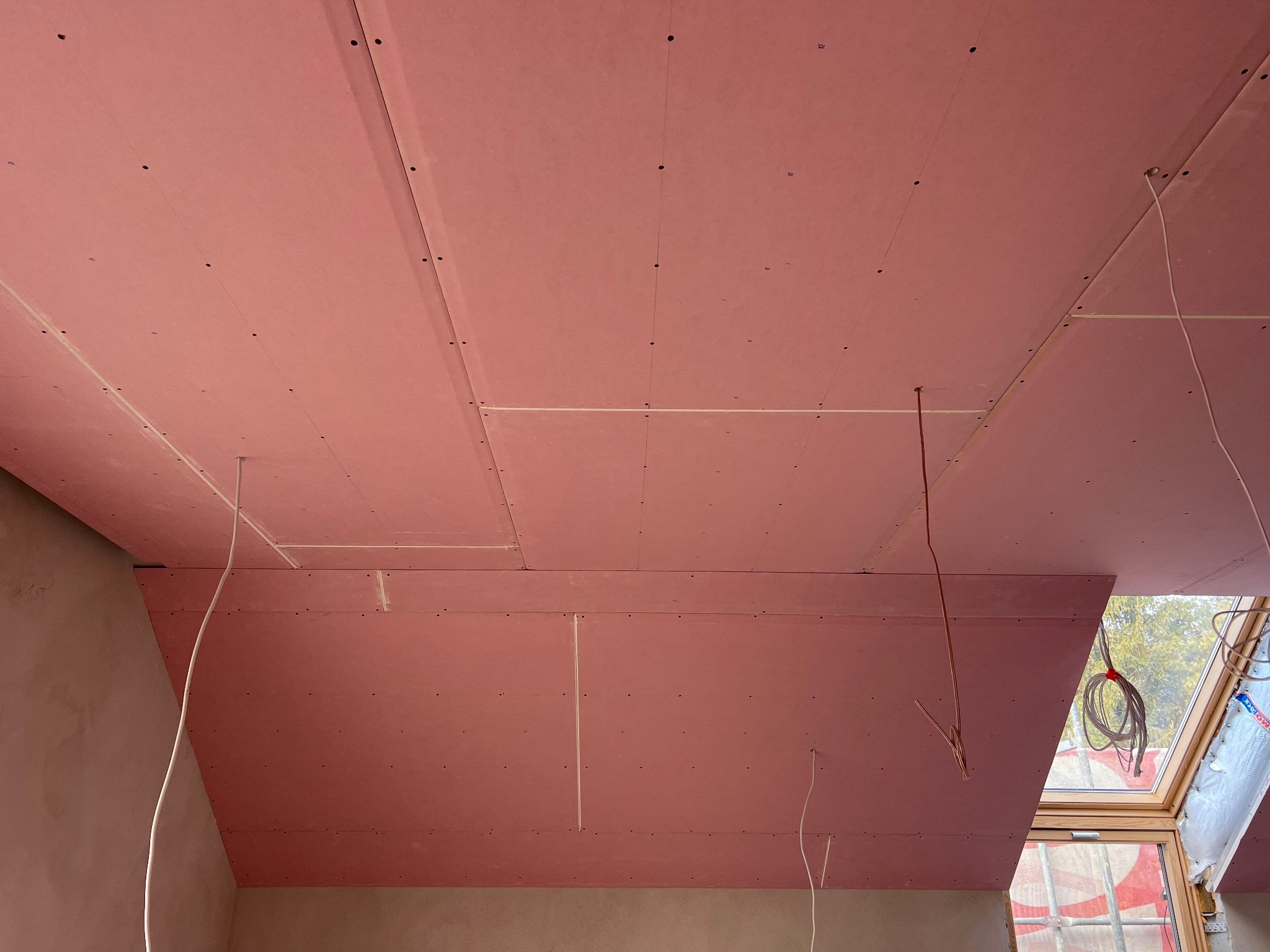 Montaż ognioodpornych płyt gipsowo-kartonowych na poddaszu, widoczne łączenia i przewody elektryczne przygotowane do dalszych prac wykończeniowych.