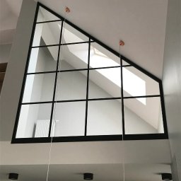 Alhen Artszkło Sp. z o.o. - Triangular okno z czarnymi szprosami w dwupoziomowym mieszkaniu, widok z dołu na poddasze z oknem dachowym.