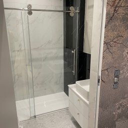 Jarosław Nitychoruk - Nowoczesna łazienka z kabiną prysznicową ze szklanymi drzwiami przesuwnymi, marmurowymi płytkami, białą szafką umywalkową i tapetą z motywem drzewa.