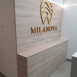Detal Meble Ksawery Stec - Recepcja kliniki dentystycznej z drewnianymi szafkami, złotym logo zęba i podświetlanym napisem 'MILANOVA DENTAL & ESTHETIC CLINIC'.