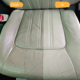 Skórzany fotel samochodowy po czyszczeniu, widoczny efekt 'przed i po', z lewej strony zabrudzony, z prawej czysty. Zapięcie pasa bezpieczeństwa widoczne po lewej stronie.