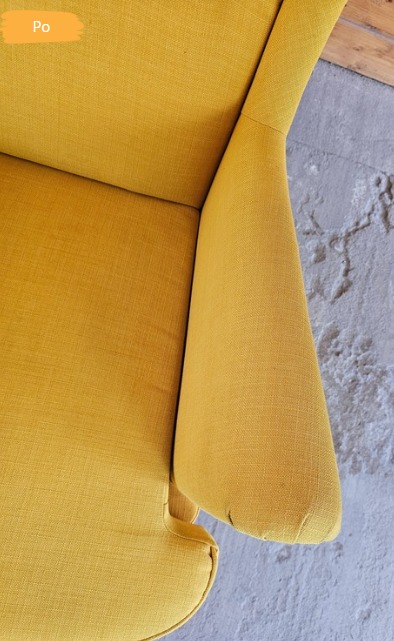 Żółty fotel tapicerowany z bliska, z widocznym efektem czyszczenia. Fragment drewnianej podłogi i betonowej ściany w tle. Oznaczenie 'Po' sugeruje stan po usłudze.