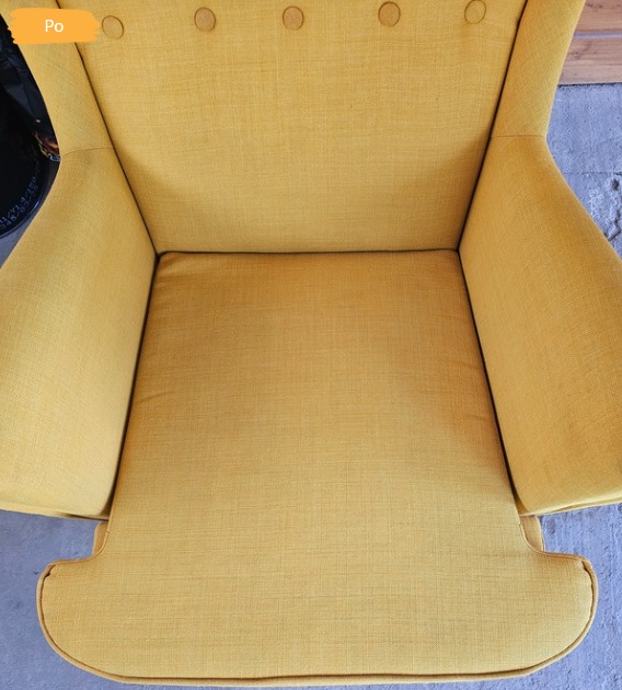 Żółty fotel typu uszak z widoczną strukturą tkaniny obiciowej i guziczkami. Zdjęcie z góry, prezentujące czystą powierzchnię po zabiegu.