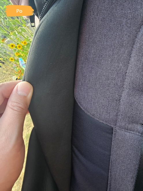 Ciemnoszara tapicerka krzesła po czyszczeniu, widoczna faktura materiału i świeżość koloru, z bliska, z fragmentem dłoni. Na zewnątrz zieleń i słońce.