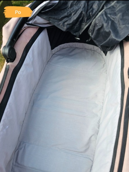 Wnętrze wózka dziecięcego po praniu tapicerki, widok z góry, czysta, jasna tkanina, element budki wózka w tle. Zdjęcie z oznaczeniem 'Po'.