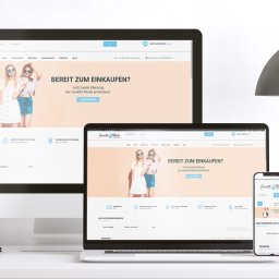 Agencja Reklamowa Szczecin Tombak Czy Złoto - Prezentacja responsywnej strony internetowej sklepu odzieżowego na monitorze, laptopie i smartfonie, z widocznym logo i ofertą 'Bereit zum Einkaufen?' w języku niemieckim.