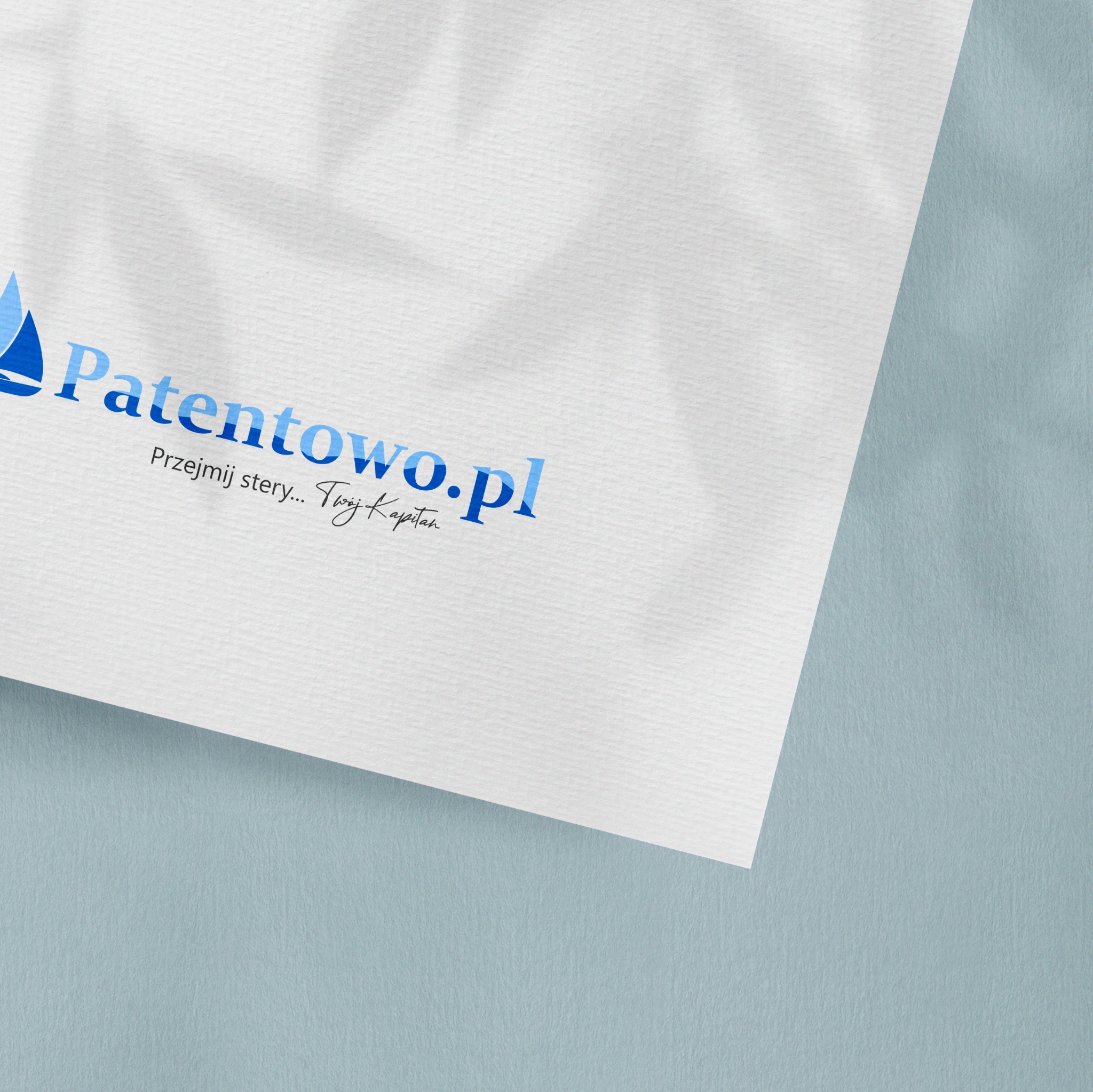 Logo firmy Patentowo.pl z motywem żaglówki i hasłem 'Przejmij stery... Twój Kapitan' na białej kartce z delikatnym cieniem liści, ułożonej na jasnoniebieskim tle.