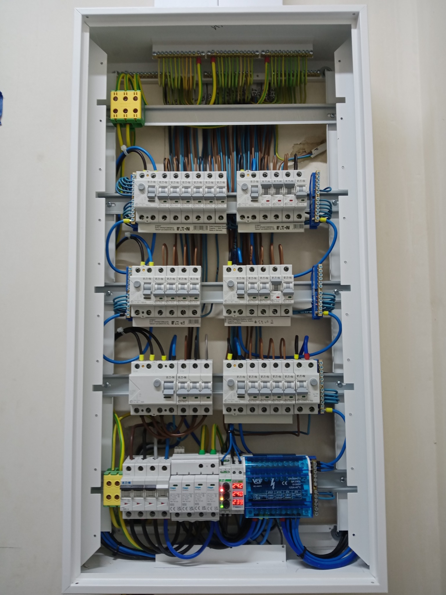 Rozdzielnica elektryczna w białej obudowie, widoczne zabezpieczenia Eaton, przewody w różnych kolorach i listwy zaciskowe. Instalacja starannie wykonana.