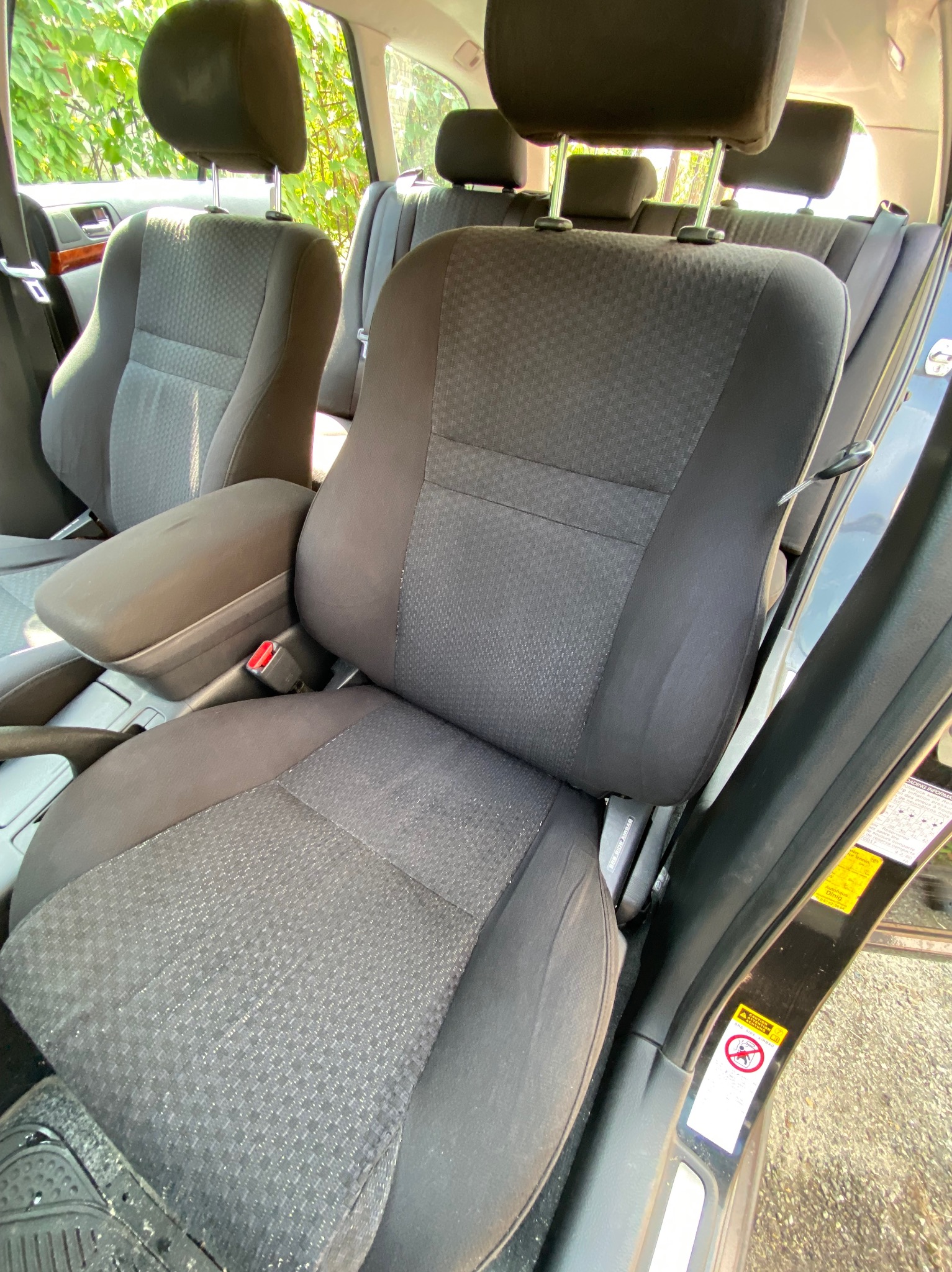 Wnętrze samochodu w Porębie z widocznymi, lekko zabrudzonymi, tekstylnymi siedzeniami i podłokietnikiem. Fotel kierowcy z widocznym pasem bezpieczeństwa, a w tle kolejne rzędy siedzeń.