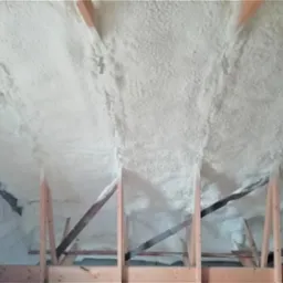 Poddasze ocieplone pianką PUR, widoczne drewniane elementy konstrukcyjne dachu i fragment ściany z bloczków.